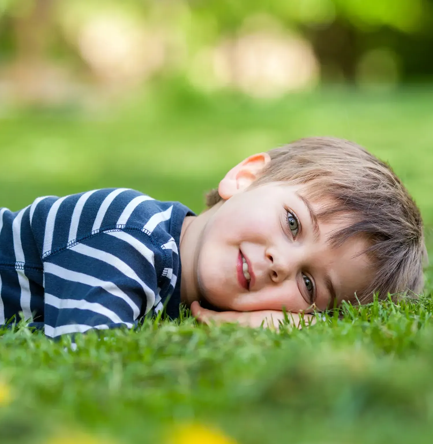 Little boy smiling while laying down on the grass